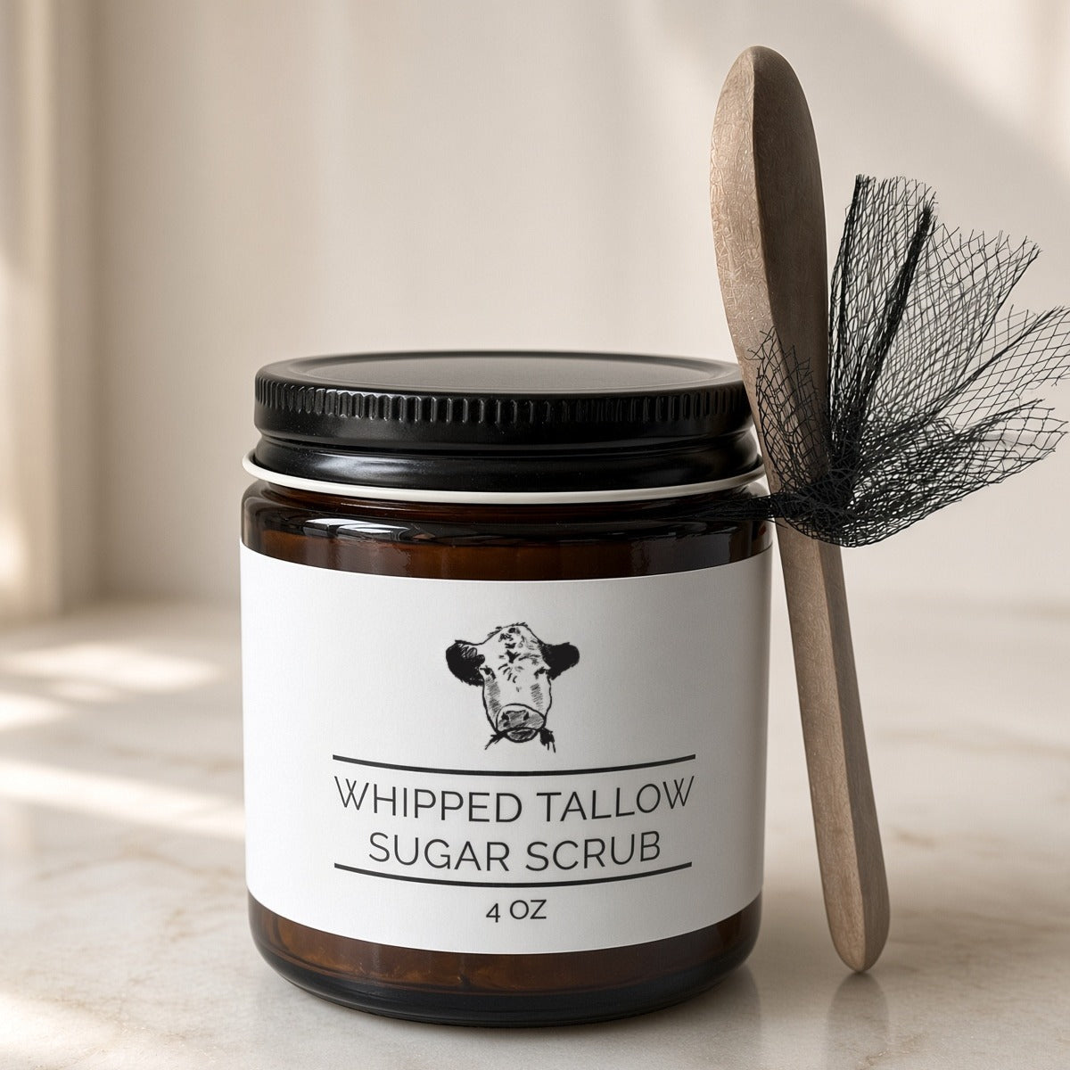 Whipped tallow sugar scrub made with grass-fed beef tallow in a 4 oz amber jar with a wooden spoon