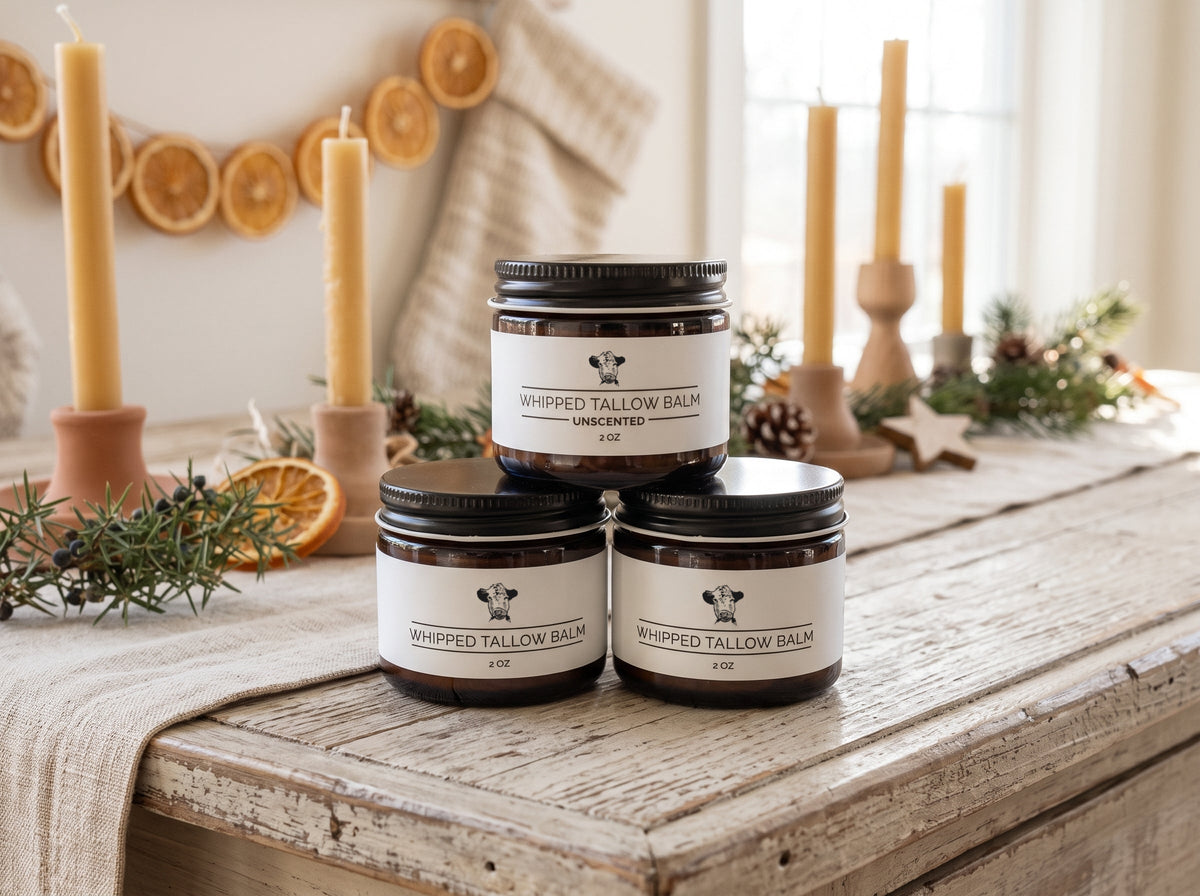 Langland Tallow Trio Gift Set: three stacked 2 oz whipped tallow balm jars, Unscented on top, on a rustic wooden table with beeswax candles, dried orange slices, pine and pinecones
