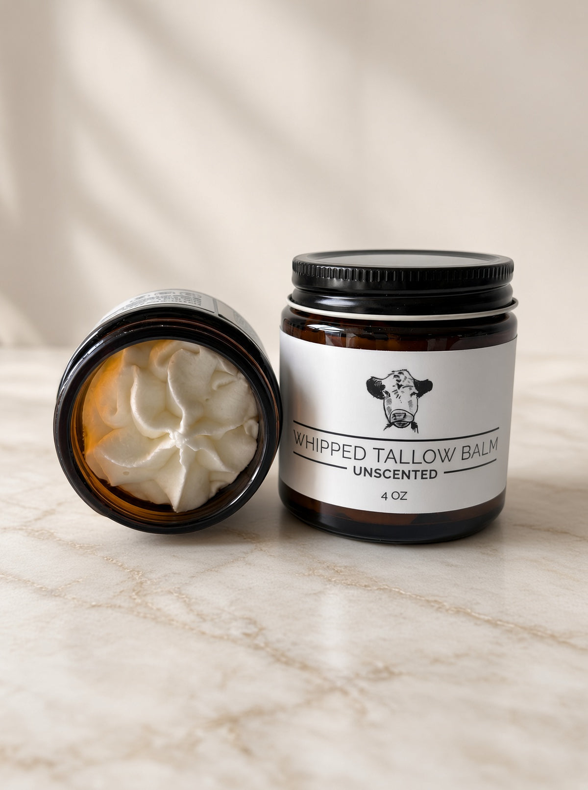 Open jar of unscented whipped tallow balm showing the whipped grass-fed tallow texture, next to a 4 oz jar